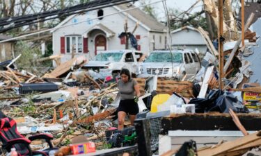 People walk among debris and fallen trees after a tornado struck on Monday in Menasha.