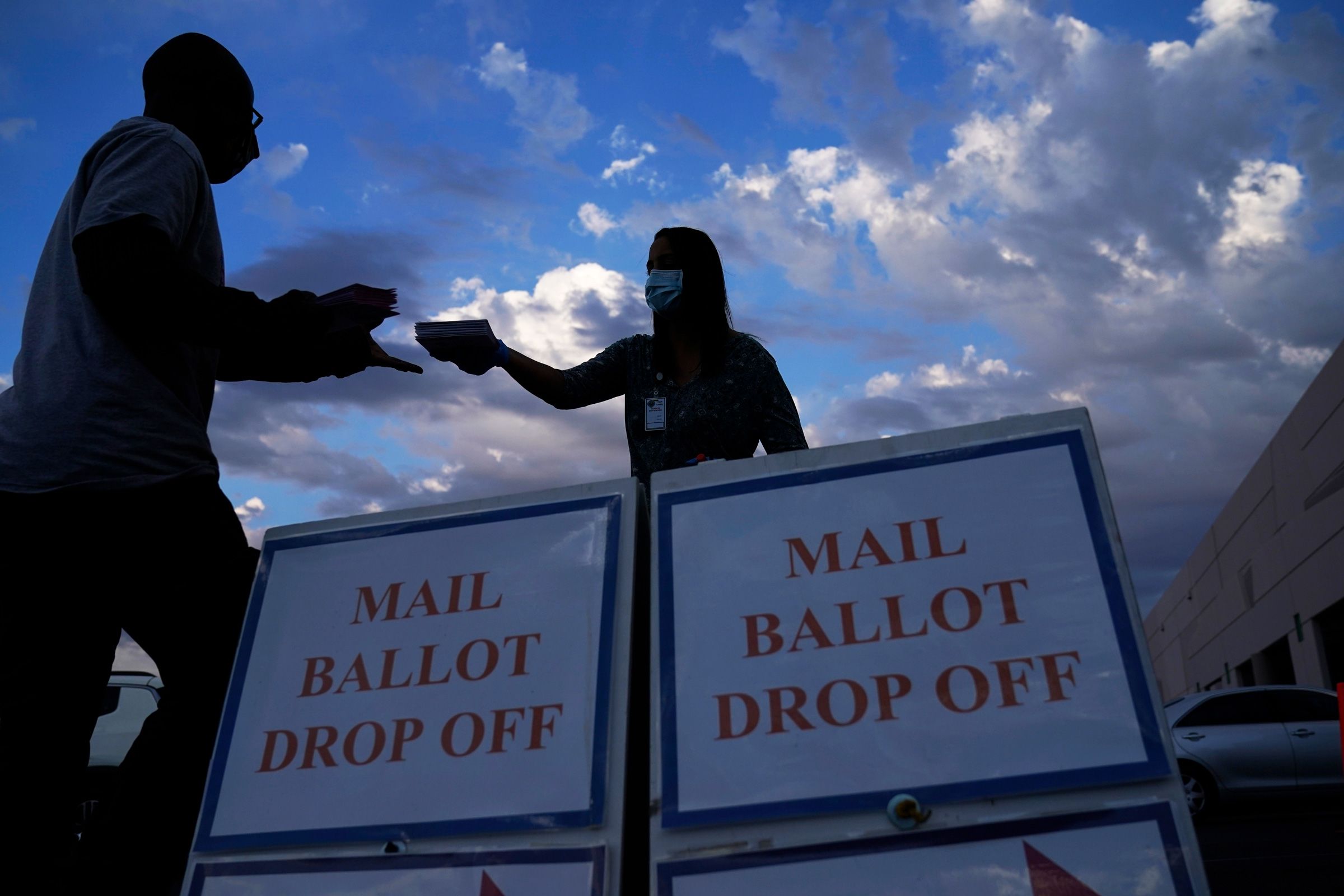 <i>John Locher/AP/File via CNN Newsource</i><br/>A county worker collects a mail-in ballots in a drive-thru mail-in ballot drop off area at the Clark County Election Department