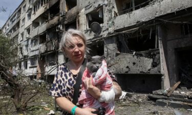 A woman with her cat stands near an apartment building hit by a Russian airstrike in the town of Pavlohrad in eastern Ukraine on July 20.