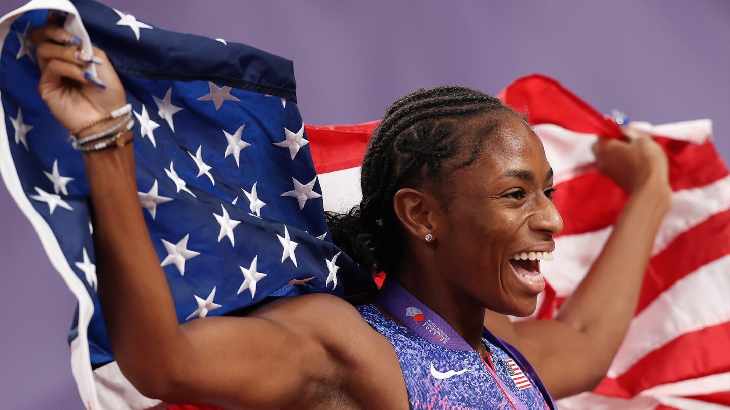 <i>NBC Olympics</i><br/>Melissa Jefferson-Wooden holds up the American flag behind her.