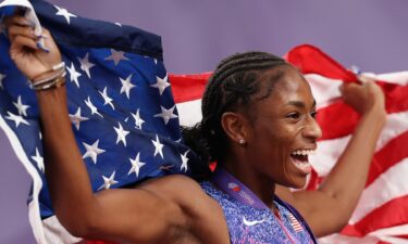 Melissa Jefferson-Wooden holds up the American flag behind her.