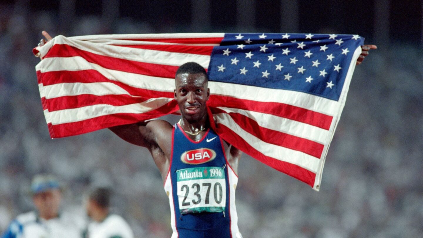 <i>NBC Olympics</i><br/>Michael Johnson holds up the American flag behind him on the track at the 1996 Atlanta Summer Olympics.