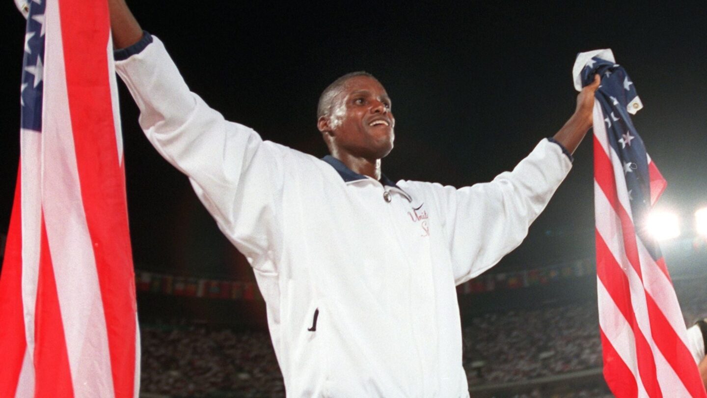 <i>NBC Olympics</i><br/>Carl Lewis celebrates with two American flags after winning the men's long jump at the 1996 Atlanta Summer Olympics.