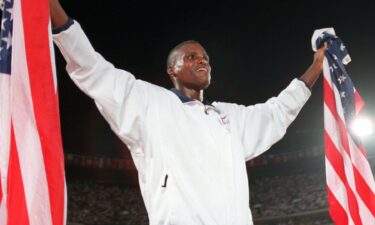 Carl Lewis celebrates with two American flags after winning the men's long jump at the 1996 Atlanta Summer Olympics.