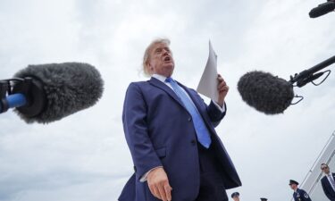US President Donald Trump holds a printed-out article as he speaks to the members of the media after disembarking Marine One