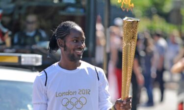 Jason Arday holds the Olympic Flame for the Torch Relay leg between Sutton and Merton boroughs in London