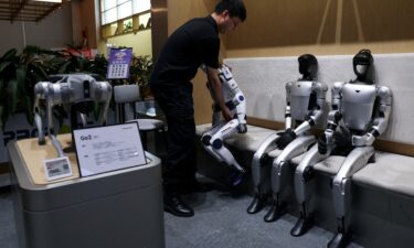 A staff member places a Unitree's R1 humanoid robot back in its seat at a Unitree store in Beijing
