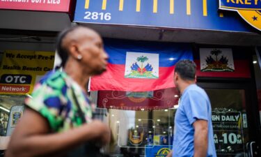 People walk past a restaurant displaying Haitian flags in the Little Haiti neighborhood of Brooklyn
