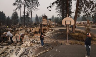 Mike Wirth holds family photos retrieved from his father-in-law's home after a wildfire hit the northwest part of Spokane