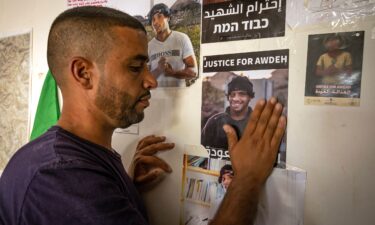 The brother of slain Palestinian activist Odeh Hathalin touches a poster calling for accountability following his killing in the occupied West Bank last year.