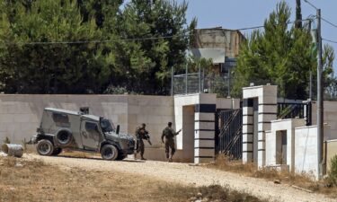 Israeli soldiers stand guard outside a Palestinian house in the village of Qusra