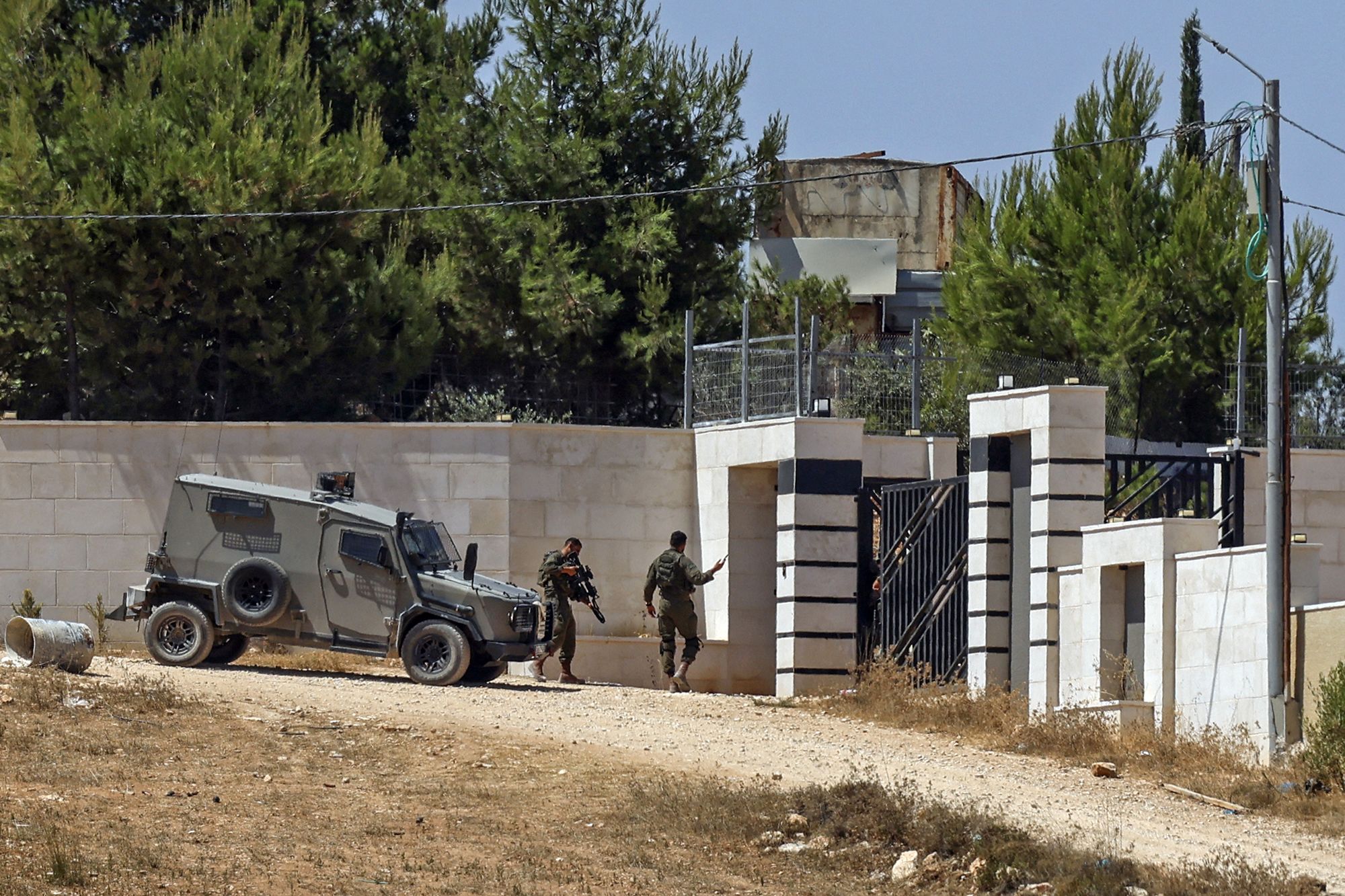 <i>Zain Jaafar/AFP/Getty Images via CNN Newsource</i><br/>Israeli soldiers stand guard outside a Palestinian house in the village of Qusra