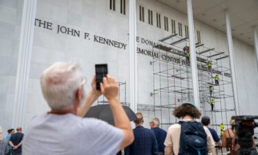 People stop to watch workers erect scaffolding at the Kennedy Center in Washington