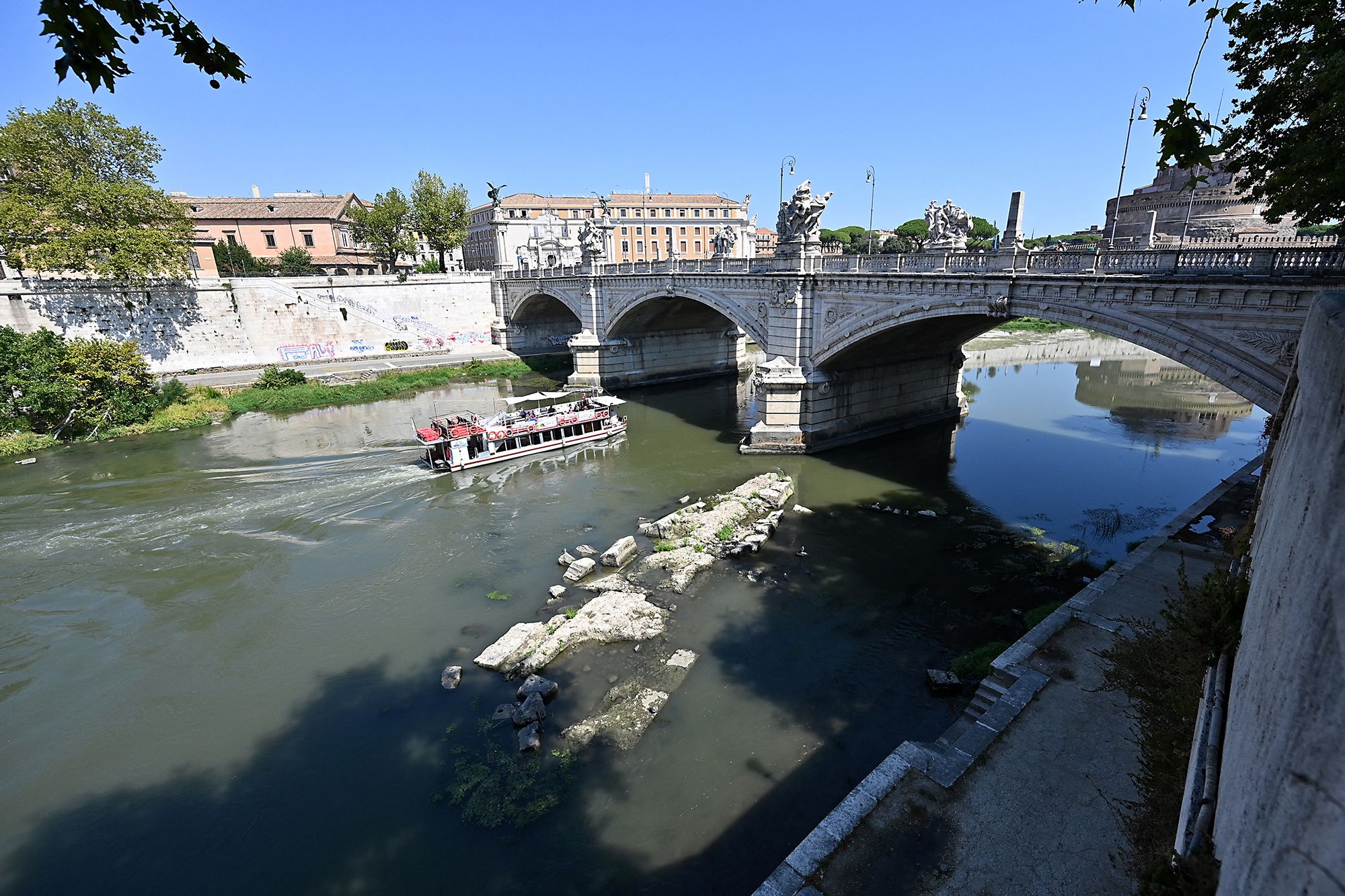 <i>Andreas Solaro/AFP/Getty Images via CNN Newsource</i><br/>A tourist boat passes near an Ancient Roman bridge emerging from the Tiber river in central Rome on August 13.