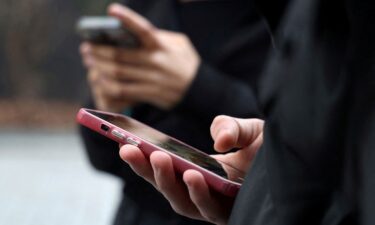 Teenagers pictured looking at their mobile phone screens in Paris.