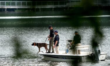 A state police boat with a dog searches the waters of Coes Pond on Friday.