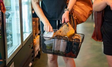 A shopper carries a basket of products at a grocery store in Wilmington