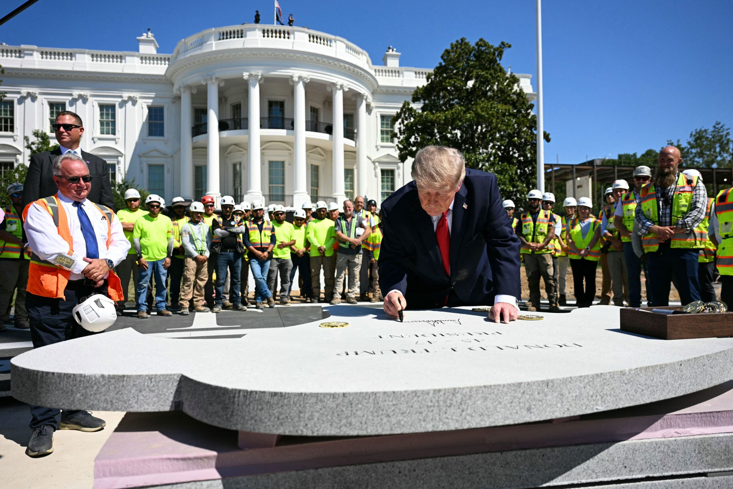 <i>Jim Watson/AFP/Getty Images via CNN Newsource</i><br/>US President Donald Trump signs a piece of stone at the construction site of a helipad on the South Lawn of the White House in Washington