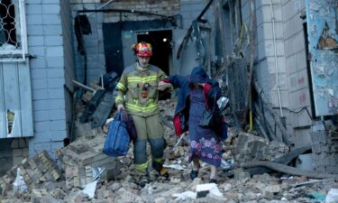 A rescuer helps a woman through the rubble after an apartment was damaged by a Russian strike in Kyiv on Thursday.