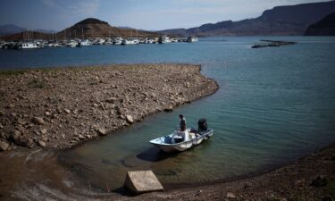 A man wades his boat into the receding shoreline of Lake Mead