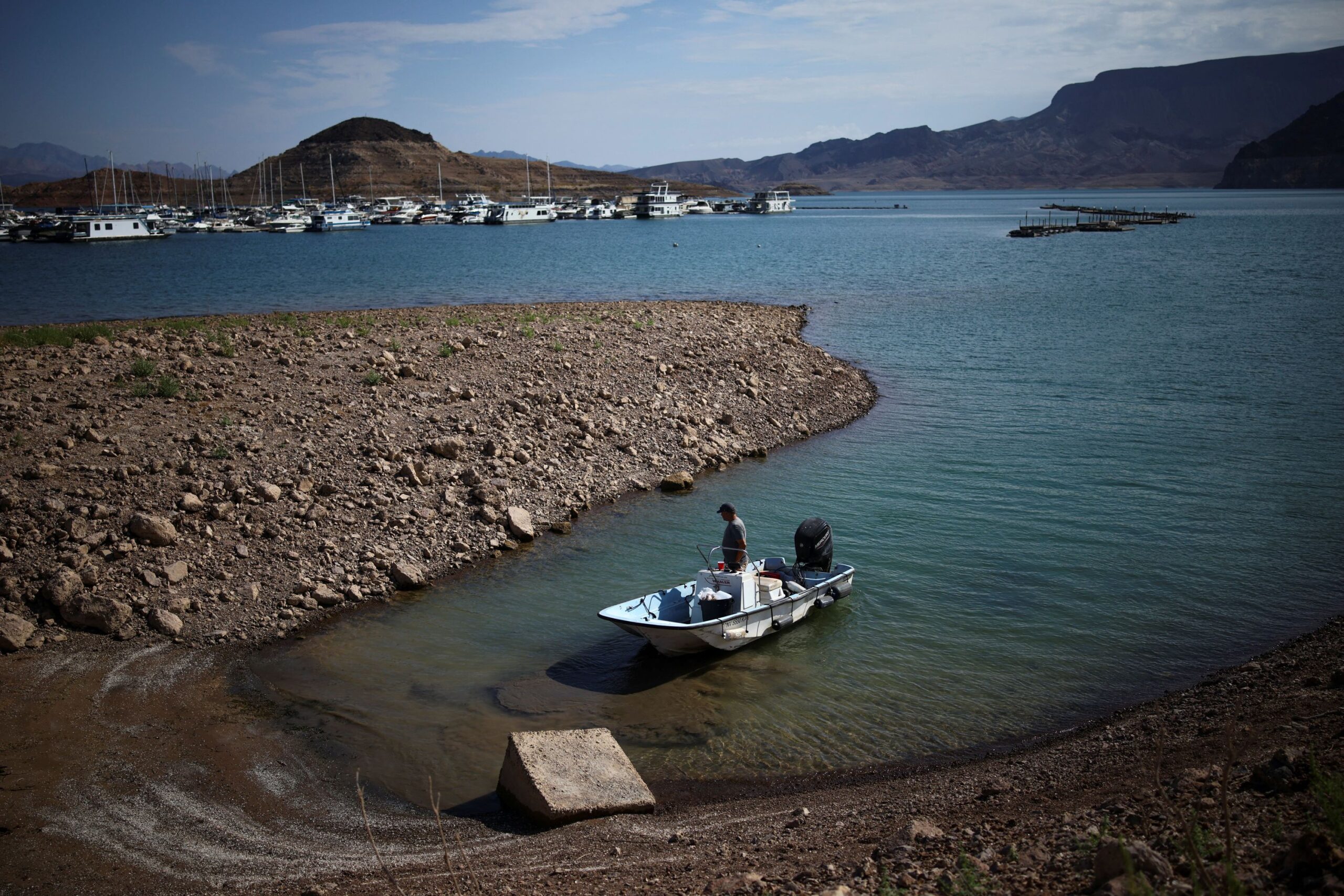 <i>Daniel Cole/Reuters via CNN Newsource</i><br/>A man wades his boat into the receding shoreline of Lake Mead