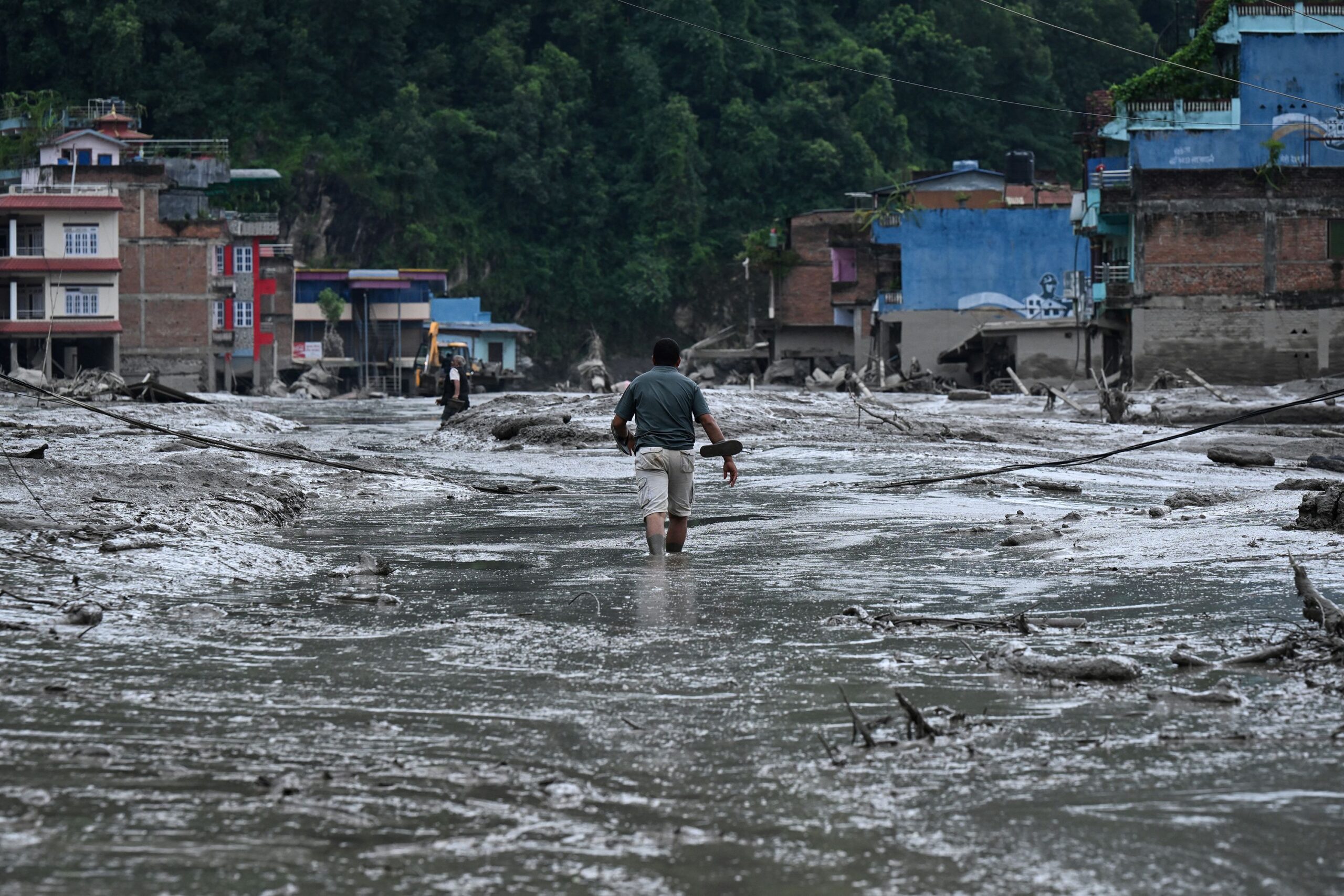<i>Ambir Tolang/NurPhoto/Getty Images via CNN Newsource</i><br/>People walk on a suspension bridge to cross the flooded Trishuli River in Bhaise