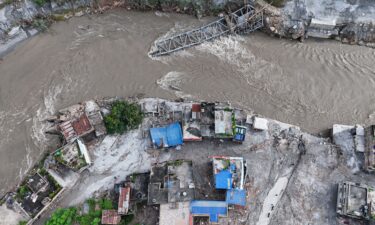 An aerial view shows a collapsed bridge and damaged settlements debris and mud covering an area following flash floods on August 28