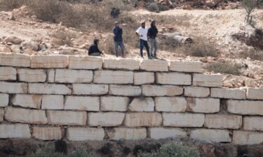 Palestinian men watch Israeli soldiers from the roof of one of the Palestinian homes besieged by Israeli settlers in Qusra on August 18.