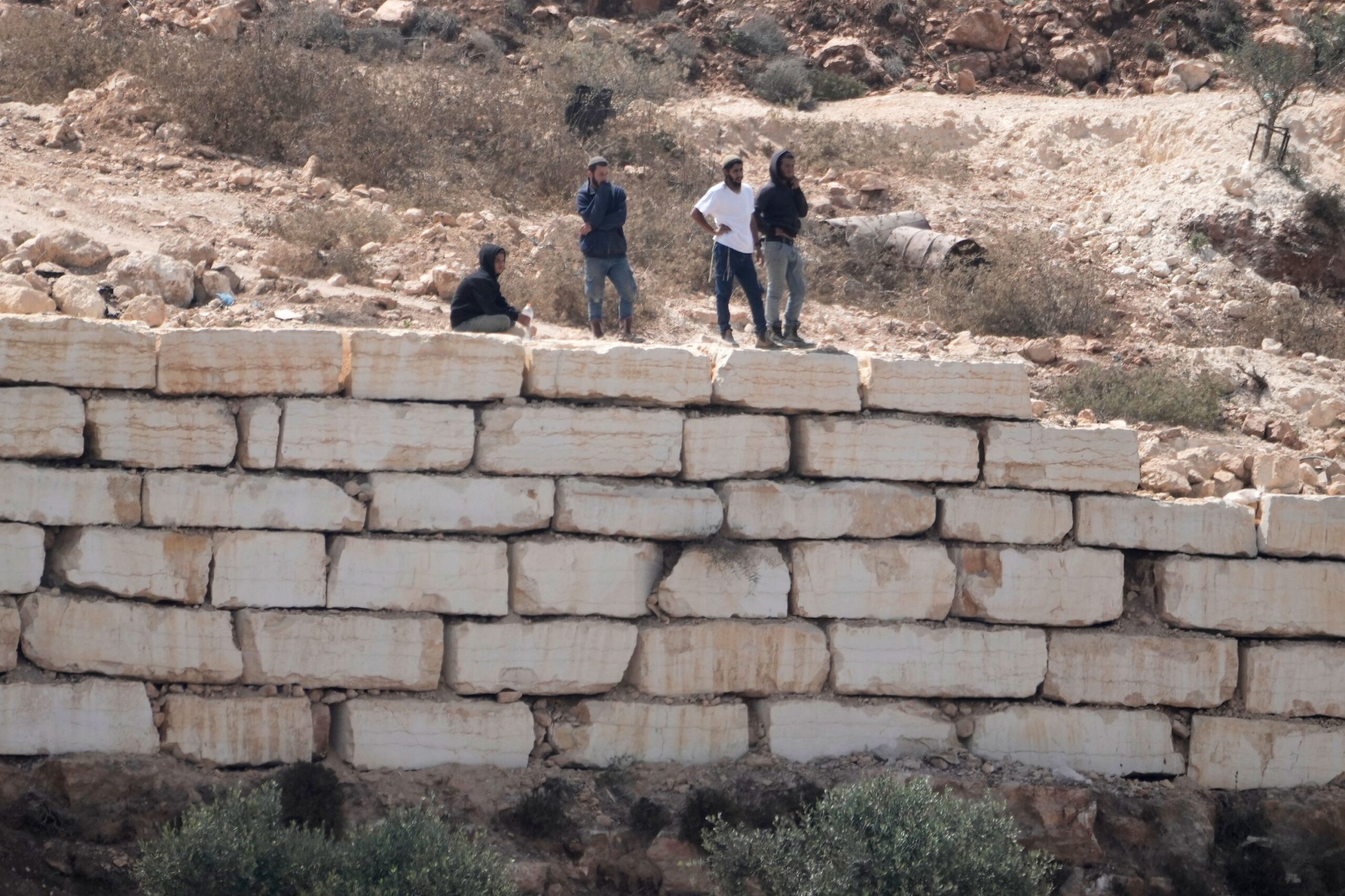 <i>Ilia Yefimovich/AFP/Getty Images via CNN Newsource</i><br/>Palestinian men watch Israeli soldiers from the roof of one of the Palestinian homes besieged by Israeli settlers in Qusra on August 18.