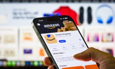 A person holds a smartphone showing the Amazon Shopping app page in the Apple App Store. The FTC and 22 states sued Amazon over advertising business practices on its vast e-commerce platform.