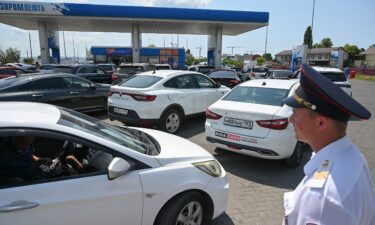 A Cossack keeps order in a line at a gas station resulting from fuel shortages following Ukrainian attacks on oil refineries