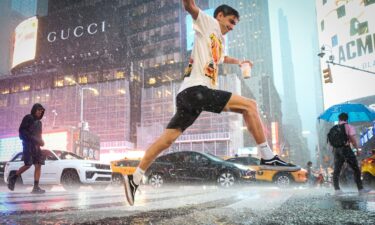 A man jumps over water in Times Square during a severe rain storm in New York on August 20.
