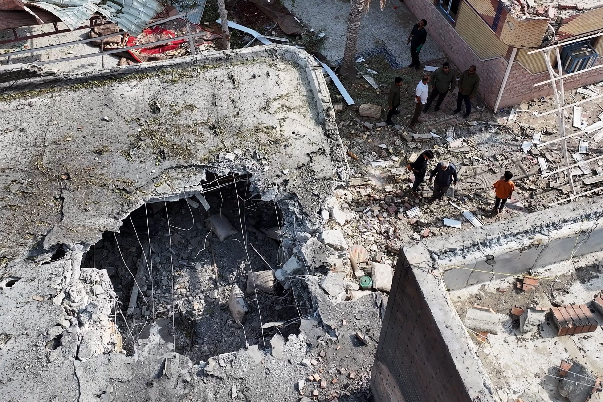 <i>Morteza Akhoondi/Tasnim News Agency/AP via CNN Newsource</i><br/>People inspect damage and debris at a building that Iranian media said was hit by a US strike while a wedding celebration was taking place there