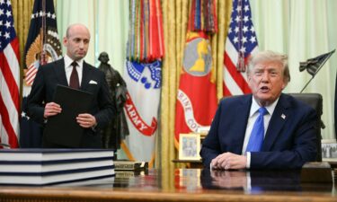 White House Deputy Chief of Staff Stephen Miller (L) holds an executive order on birthright citizenship as US President Donald Trump speaks before signing it in the Oval Office of the White House in Washington