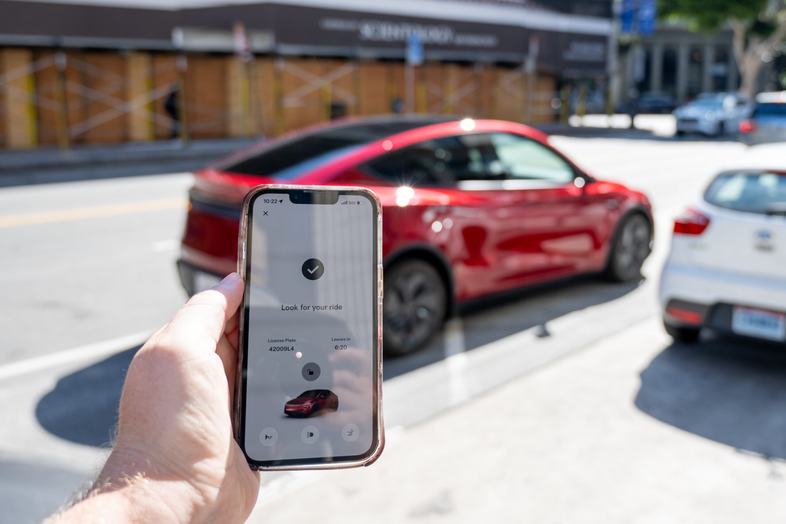 <i>Smith Collection/Gado/Getty Images via CNN Newsource</i><br/>A smartphone displays the Tesla Robotaxi app while a Tesla Robotaxi Model Y self-driving vehicle arrives for pickup in San Francisco