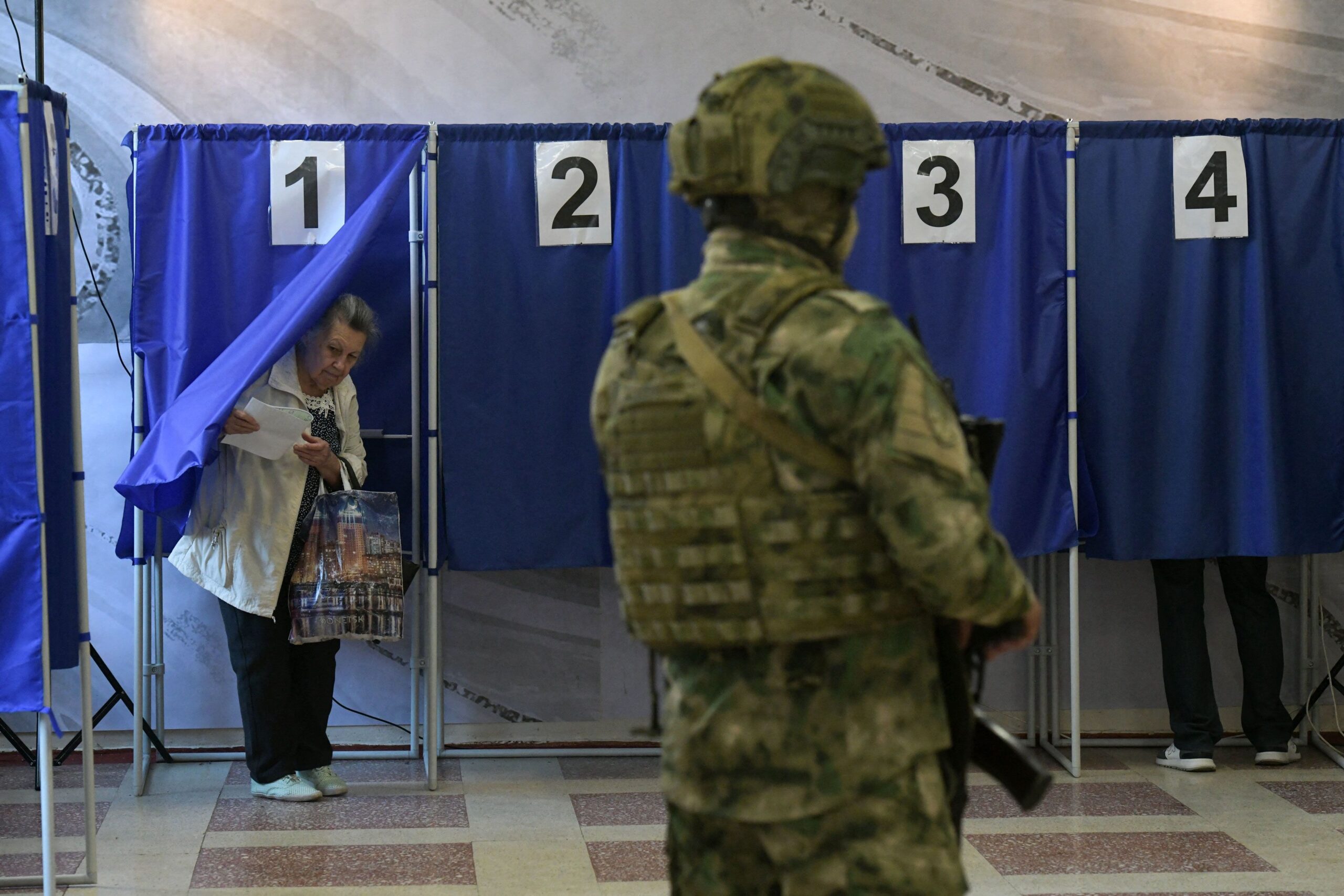 <i>Stringer/AFP/Getty Images via CNN Newsource</i><br/>People vote in Russia's parliamentary election as a Russian serviceman secures a polling station in Donetsk