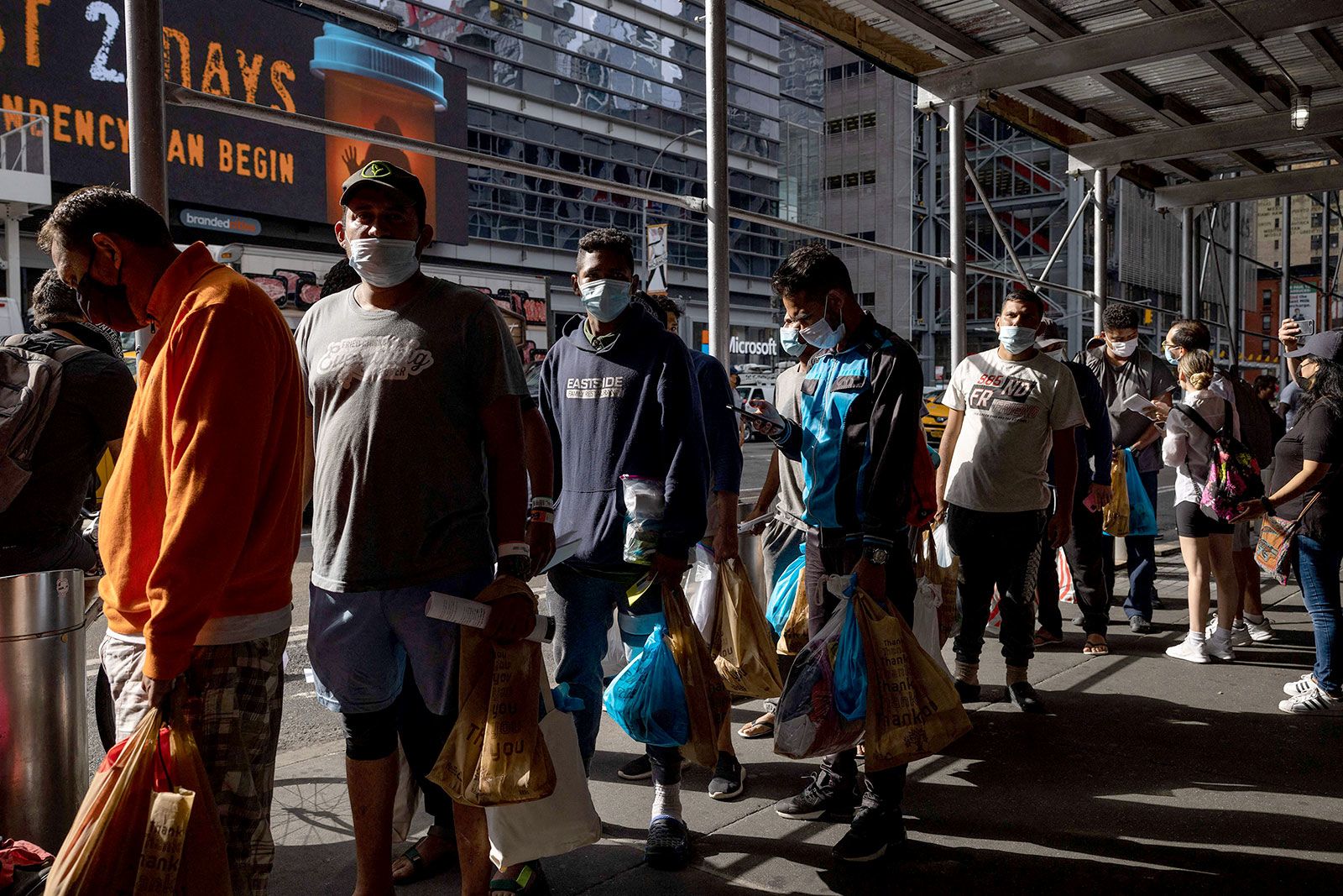 <i>Yuki Iwamura/AFP/Getty Images via CNN Newsource</i><br/>A group of migrants wait in line after arriving from Texas