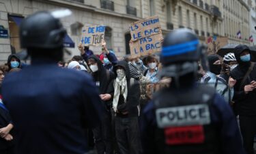 Police stand guard as a student holds a board reading 'they want the BAC (High School Diploma) Not the BAC (Anti-criminality units)' during a protest against under-resourced schools