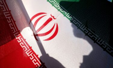 An Islamic Revolutionary Guard Corps personnel holds an Iranian national flag while preparing to take part in a military parade in southern Tehran