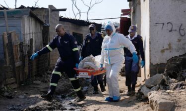 Police officers carry the body of a person on a stretcher after a mass shooting at an informal settlement in the Cleveland suburb of Johannesburg