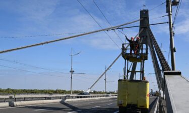 Technicians repair a trolleybus power line that was damaged following a Russian strike on the Northern Bridge in Kyiv on October 3.