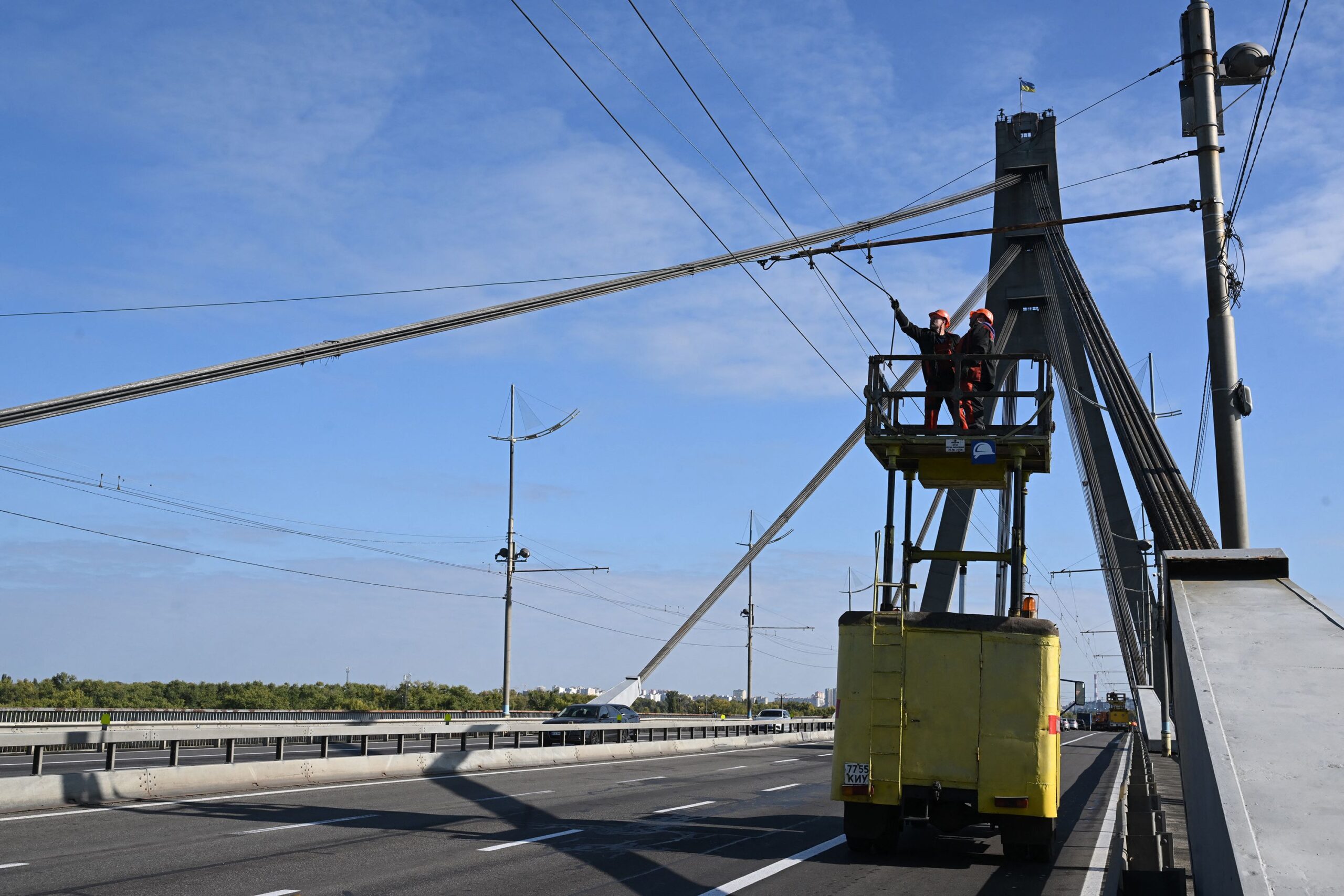 <i>Sergei Supinsky/AFP/Getty Images via CNN Newsource</i><br/>Technicians repair a trolleybus power line that was damaged following a Russian strike on the Northern Bridge in Kyiv on October 3.