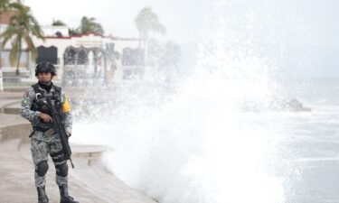 A member of Mexico's National Guard stands on the Puerto Vallarta boardwalk as waves crash against the shoreline ahead of the potential impact of Hurricane Simon in Puerto Vallarta