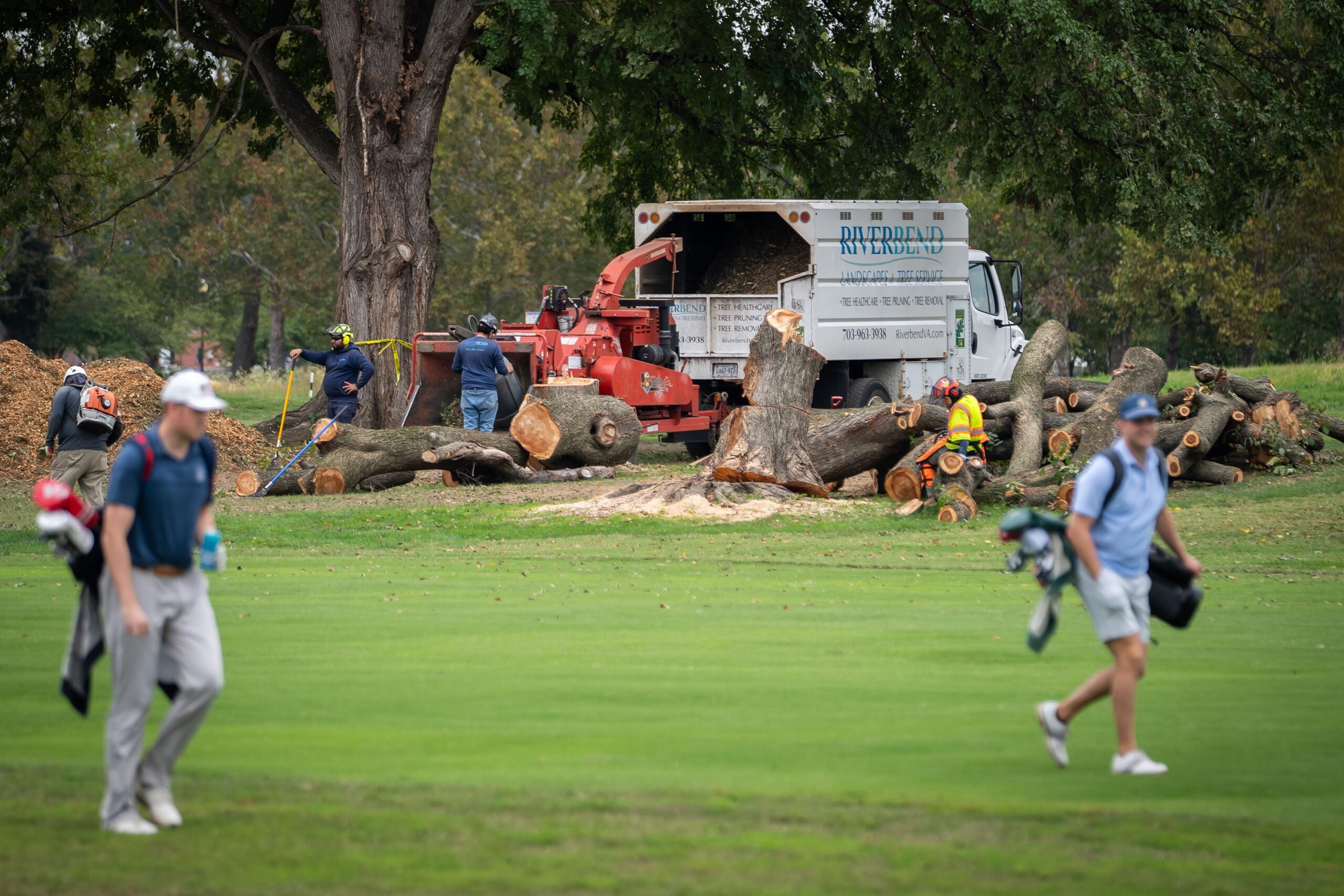 <i>Nathan Howard/AP via CNN Newsource</i><br/>Golfers pass workers as trees are cut down at East Potomac Golf Links