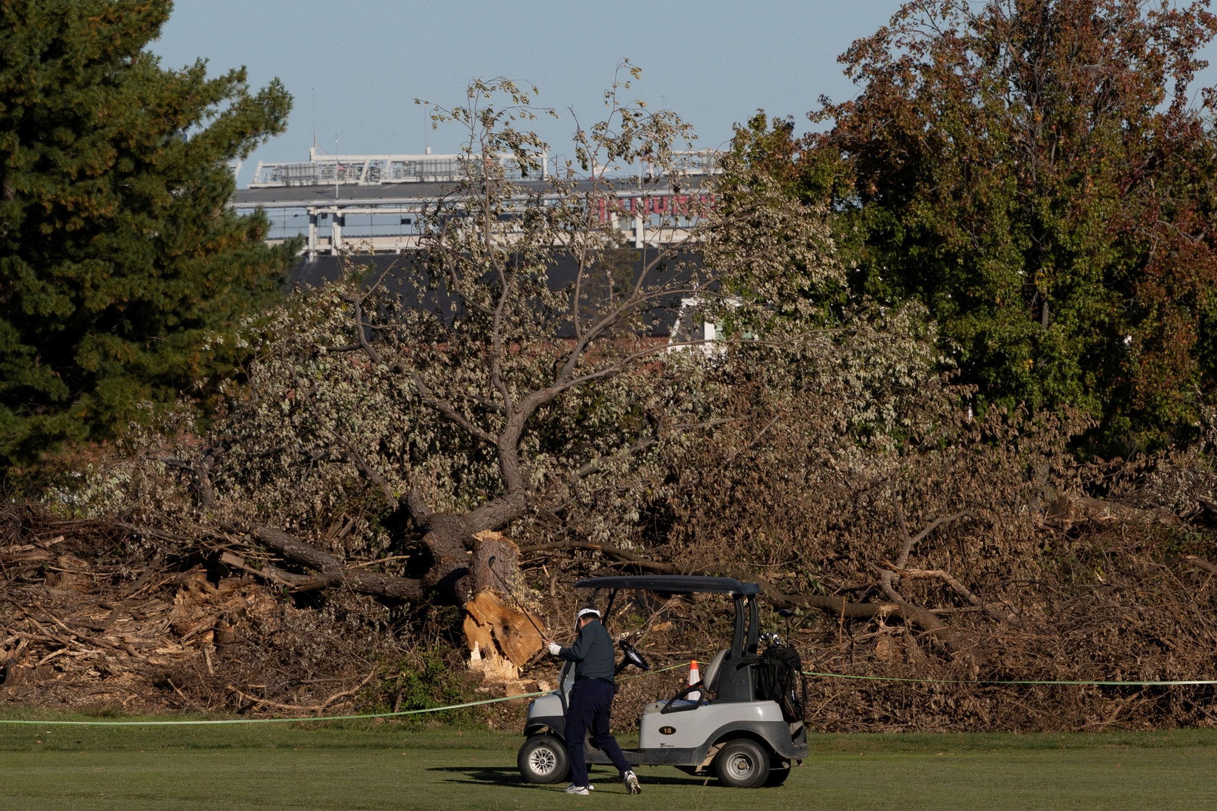 <i>Umit Bektas/Reuters via CNN Newsource</i><br/>A golfer plays near felled trees at East Potomac Golf Links in Washington