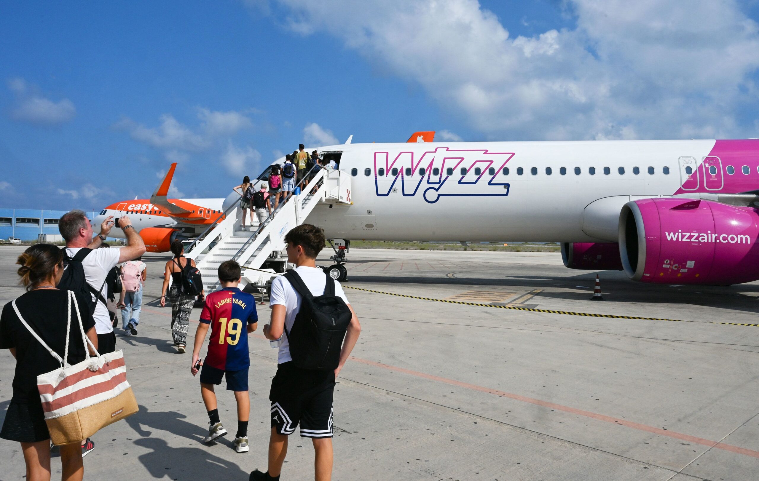 <i>Stefano Rellandini/AFP/Getty Images via CNN Newsource</i><br/>Passengers embark a Wizz air jet at the Lampedusa airport