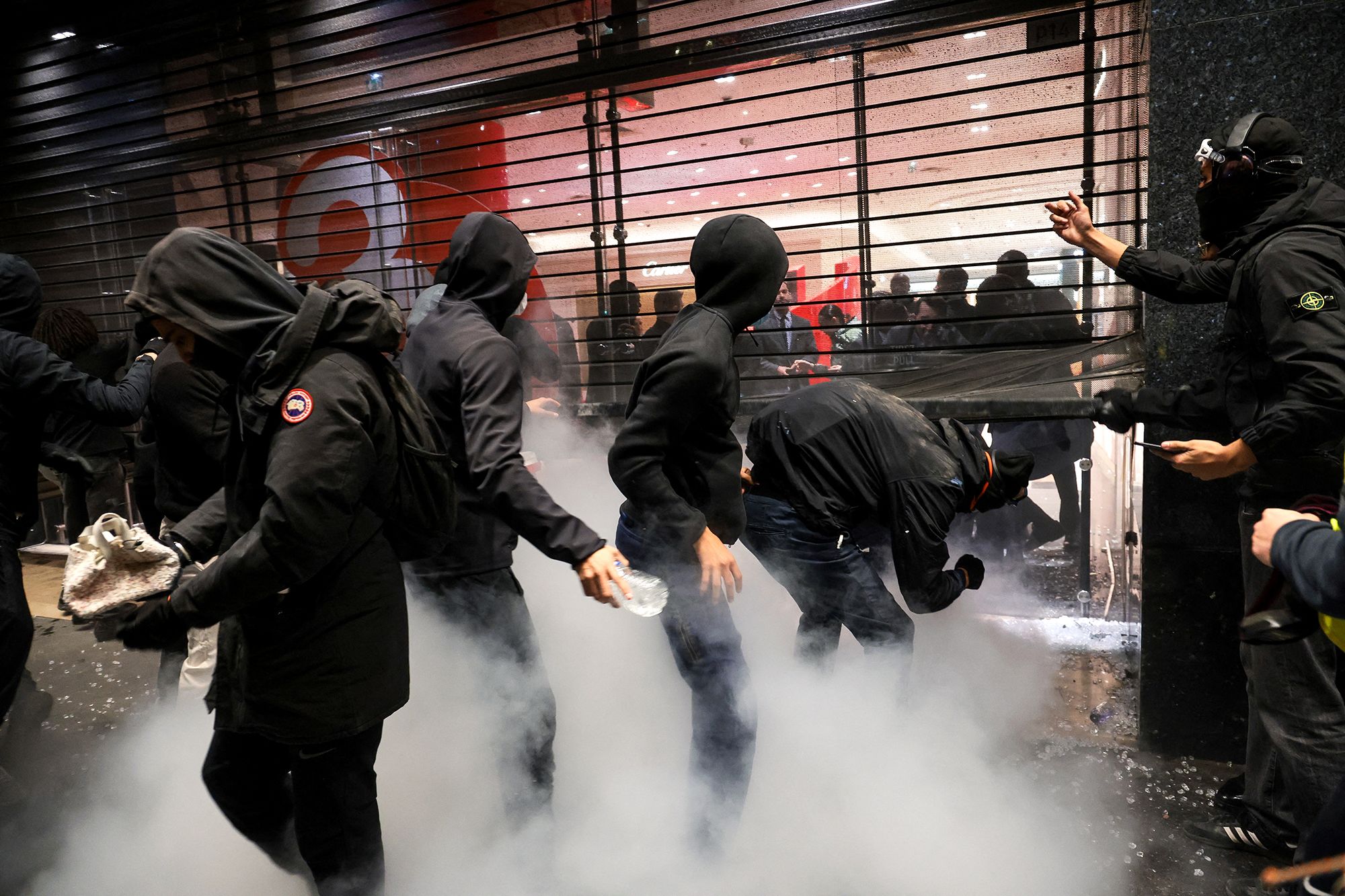 <i>Gauthier Bedrignans/Hans Lucas/AFP/Getty Images via CNN Newsource</i><br/>Masked protesters force a metal grid to the Galeries Lafayette to loot items in Paris on Oct. 17