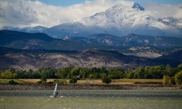 A windsurfer cuts across McIntosh Lake in front of the snow covered peaks of Mount Meeker and Longs Peak in Longmont
